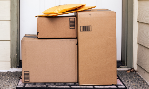 Cardboard boxes stacked and delivered at a doorstep.
